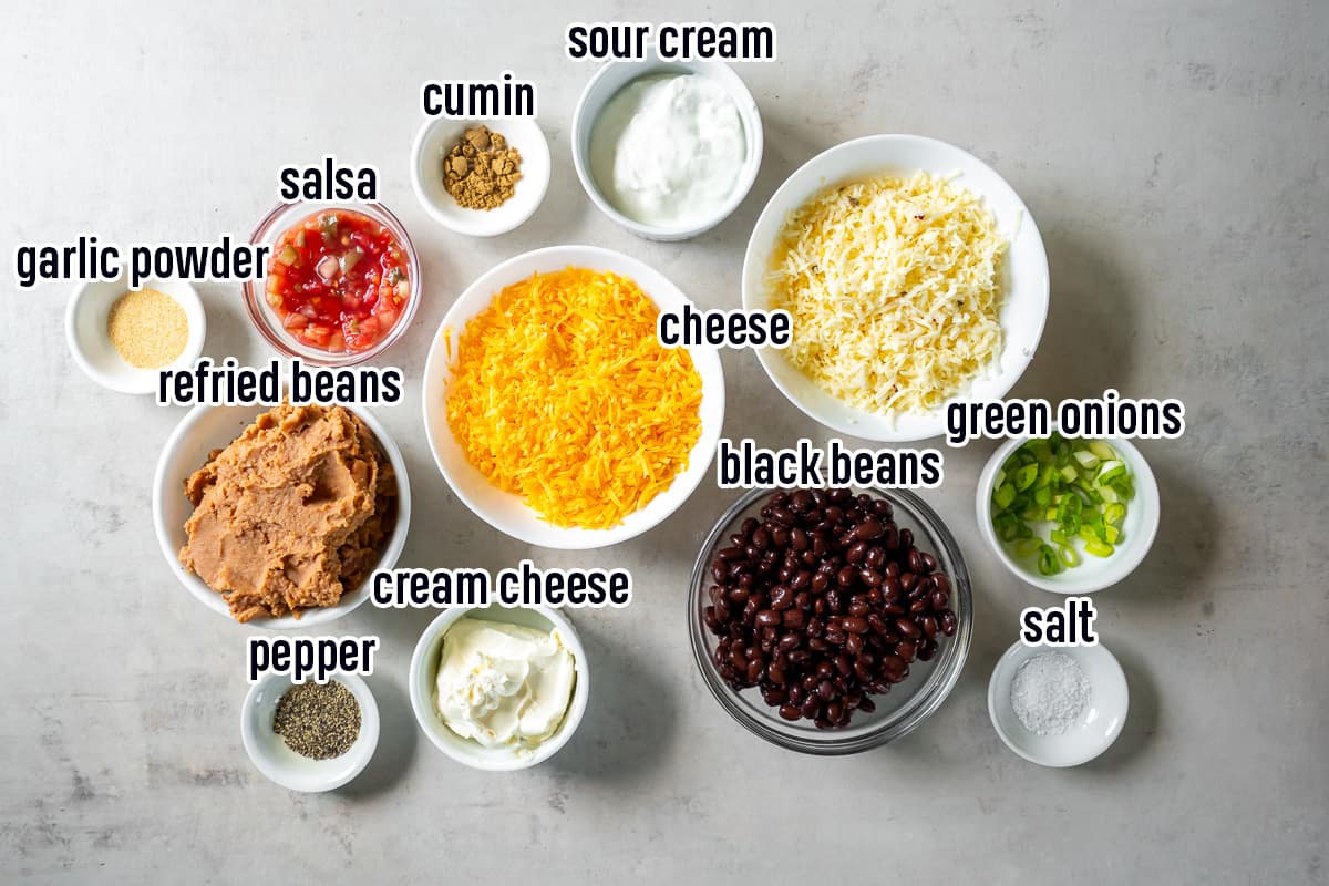 Shredded cheese, refried beans, black beans and other ingredients in bowls with text.