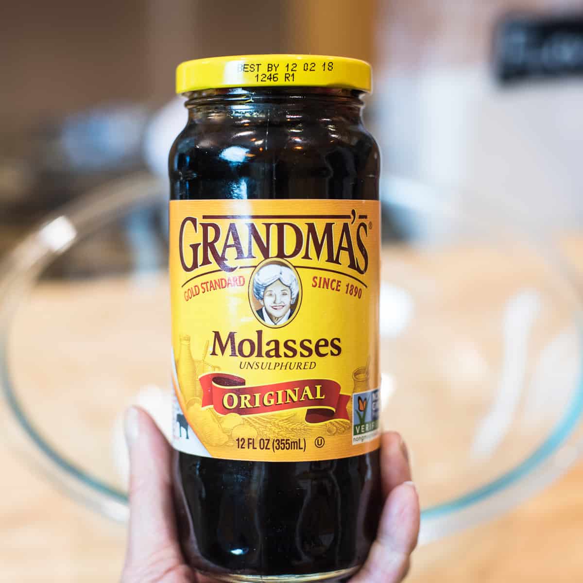 A hand holding a jar of Grandma's Molasses Unsulphured.