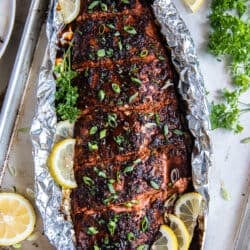 A top down shot of a glazed sockeye salmon fillet on foil with lemon slices.