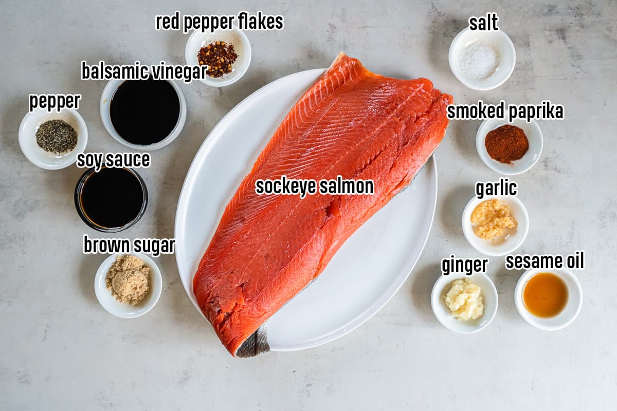 A whole sockeye salmon fillet on a plate surrounded by glaze ingredients in bowls with text.