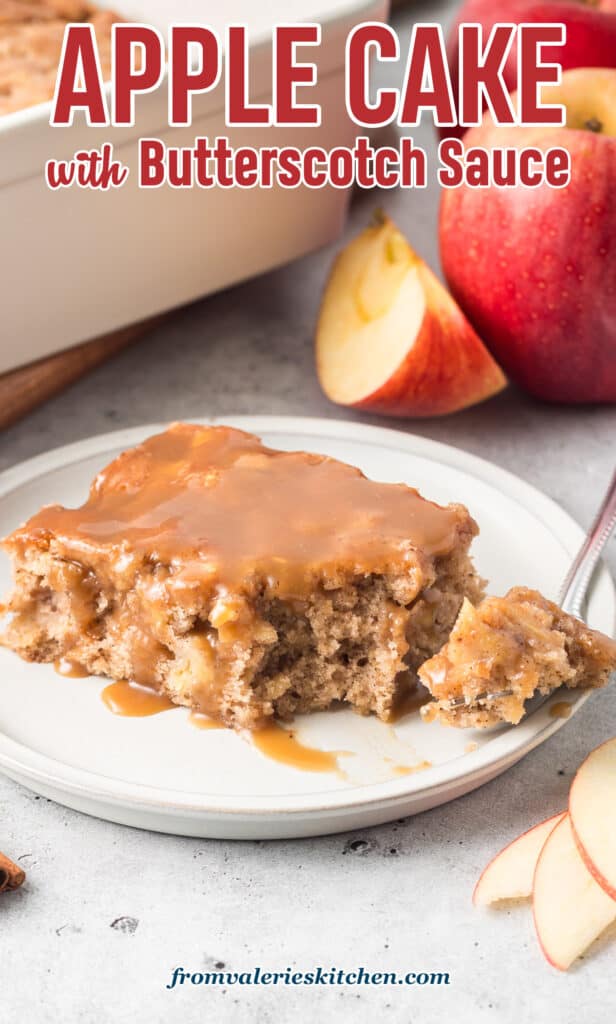 A slice of apple cake with butterscotch sauce on a white plate with a fork with text.