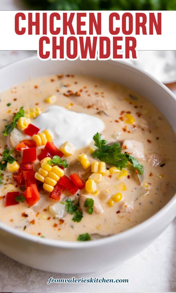 A close up of a bowl of chicken corn chowder topped with sour cream and diced bell peppers with text.