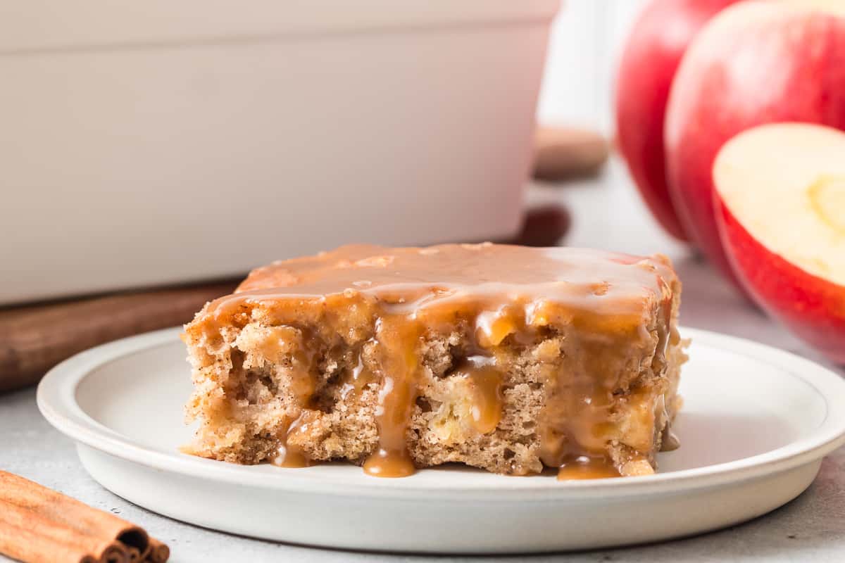 A side view of a slice of apple cake topped with butterscotch caramel sauce.