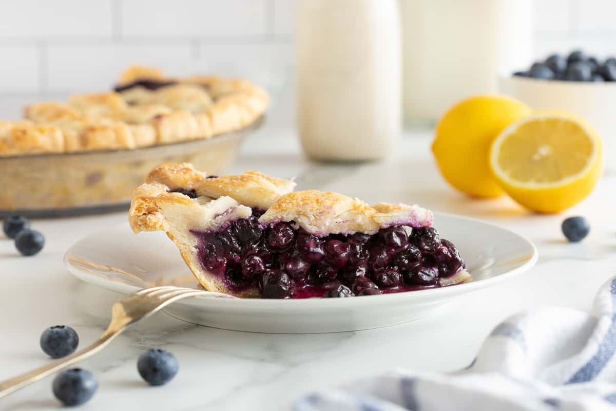 A side view of a slice of blueberry pie on a small plate.