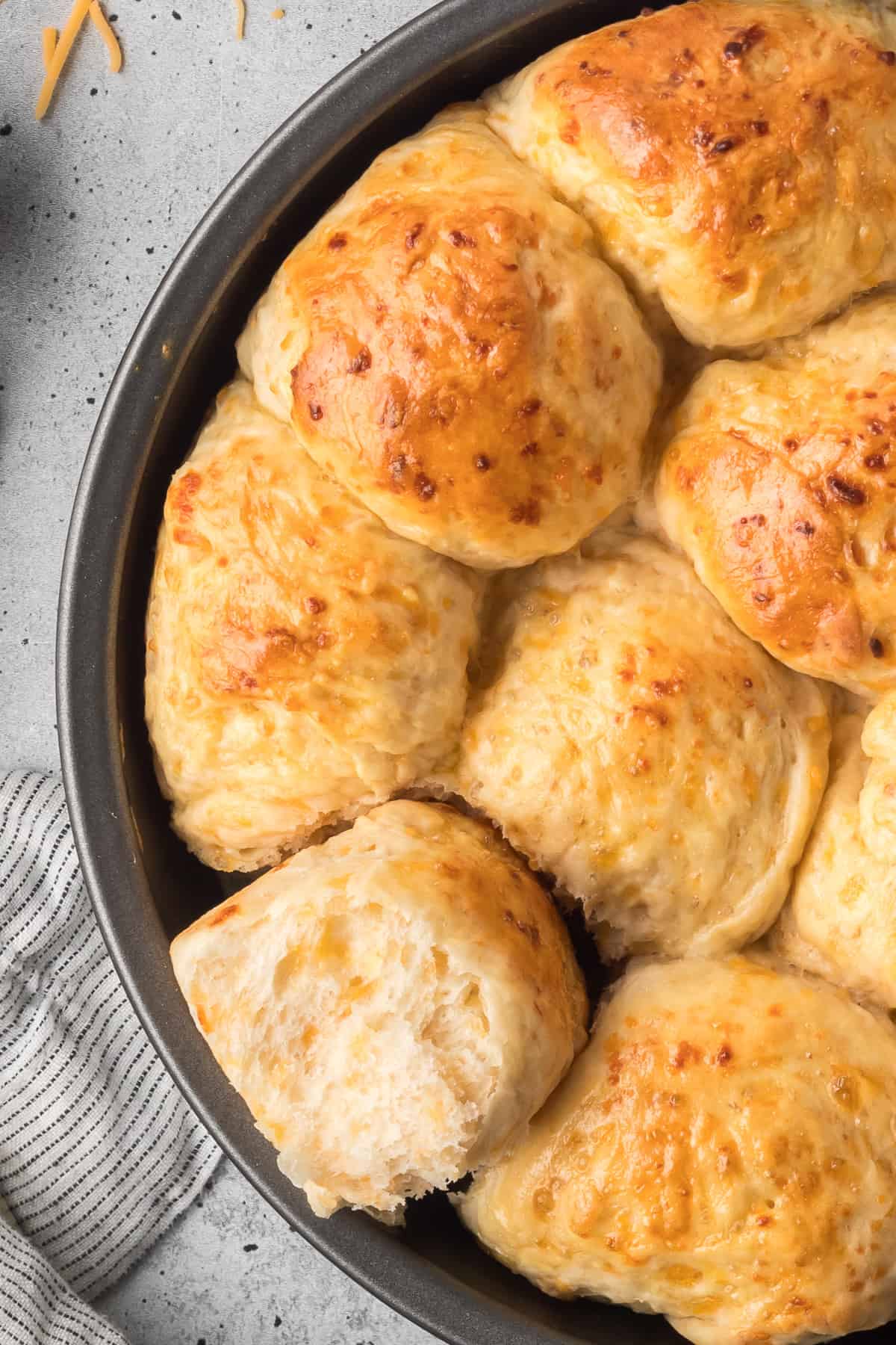 A close up top down shot of cheddar dinner rolls in a metal cake pan.