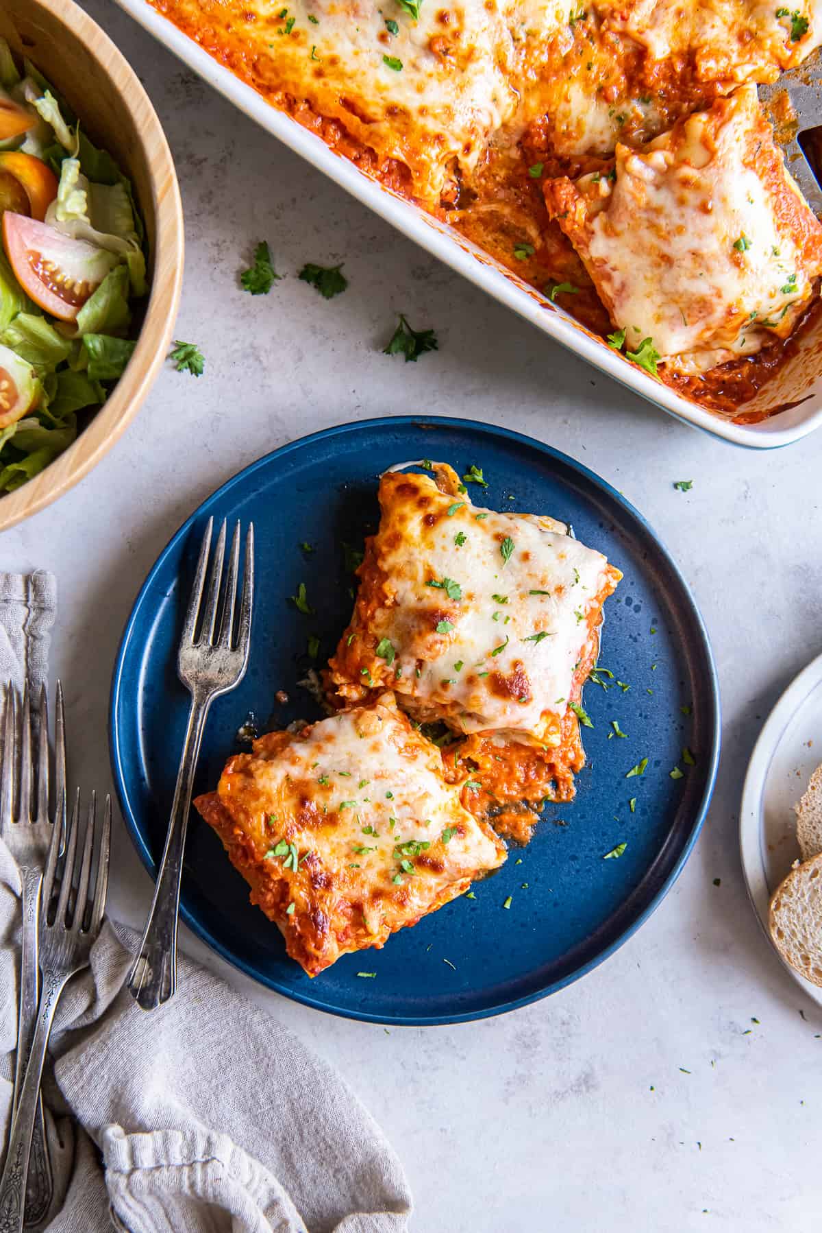 A top down shot of two lasagna roll ups on a blue plate with a fork.