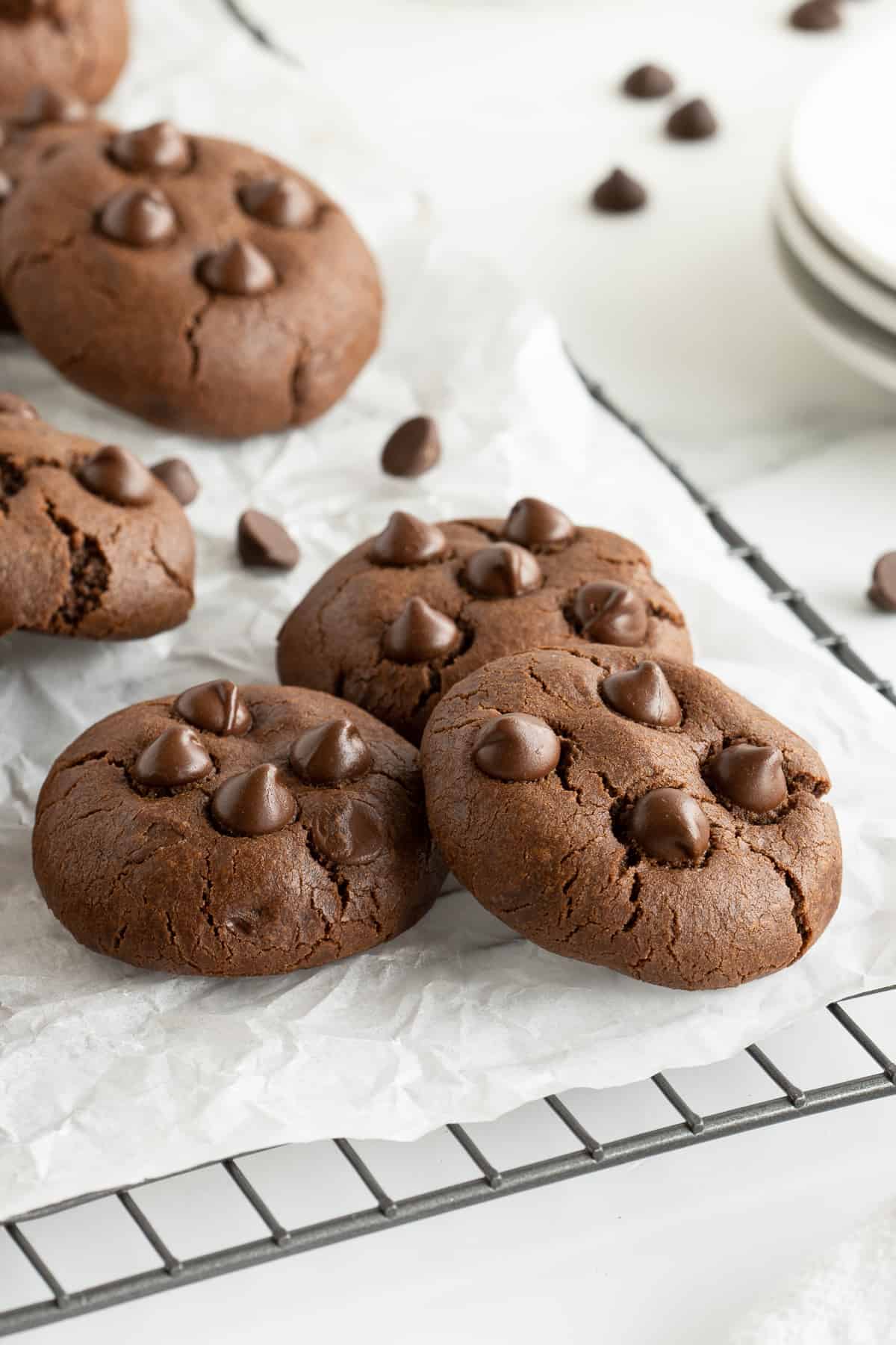 A side view of three double chocolate cookies on a wire rack.