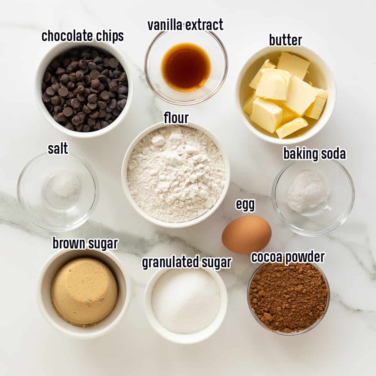 Chocolate chips, cocoa powder, flour, sugar and other ingredients in bowls with text.