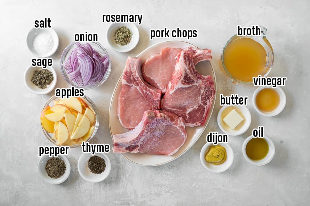 A top down shot of pork chops on a plate surrounded by sliced apples, onions, and other ingredients in small bowls with text.