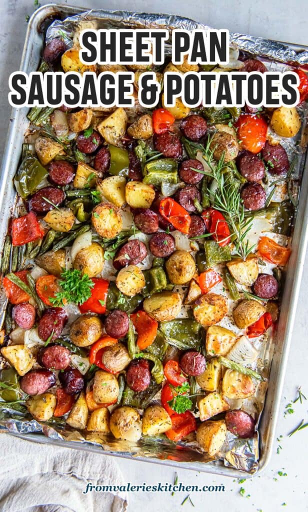 Sausage and potatoes with bell peppers and green beans on a baking sheet with text.
