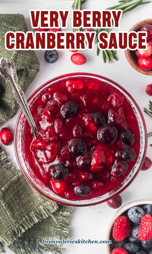 A top down shot of berry cranberry sauce in a glass bowl with a spoon with text.