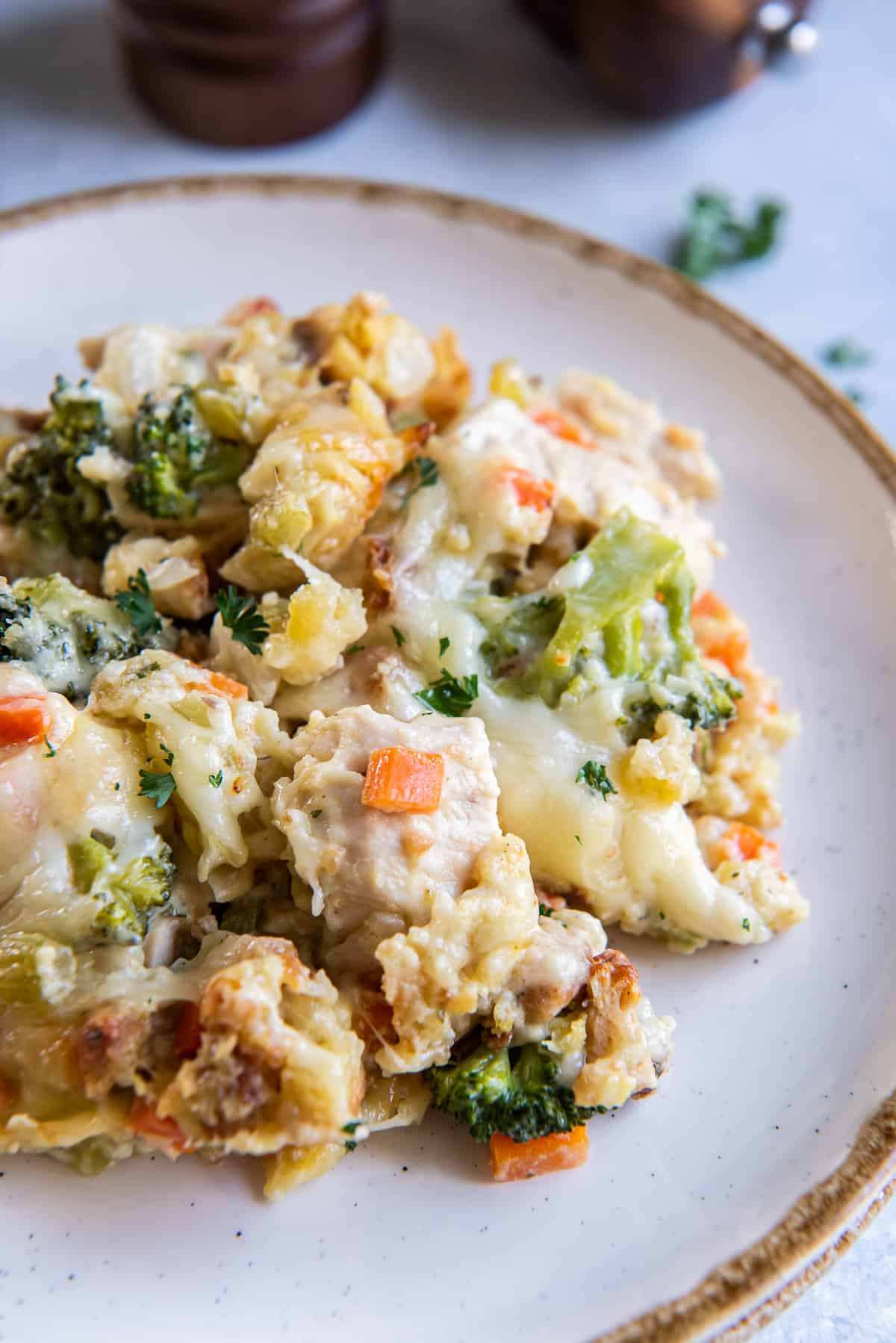A serving of chicken stuffing bake with broccoli and cheese on a white plate with a brown trim.