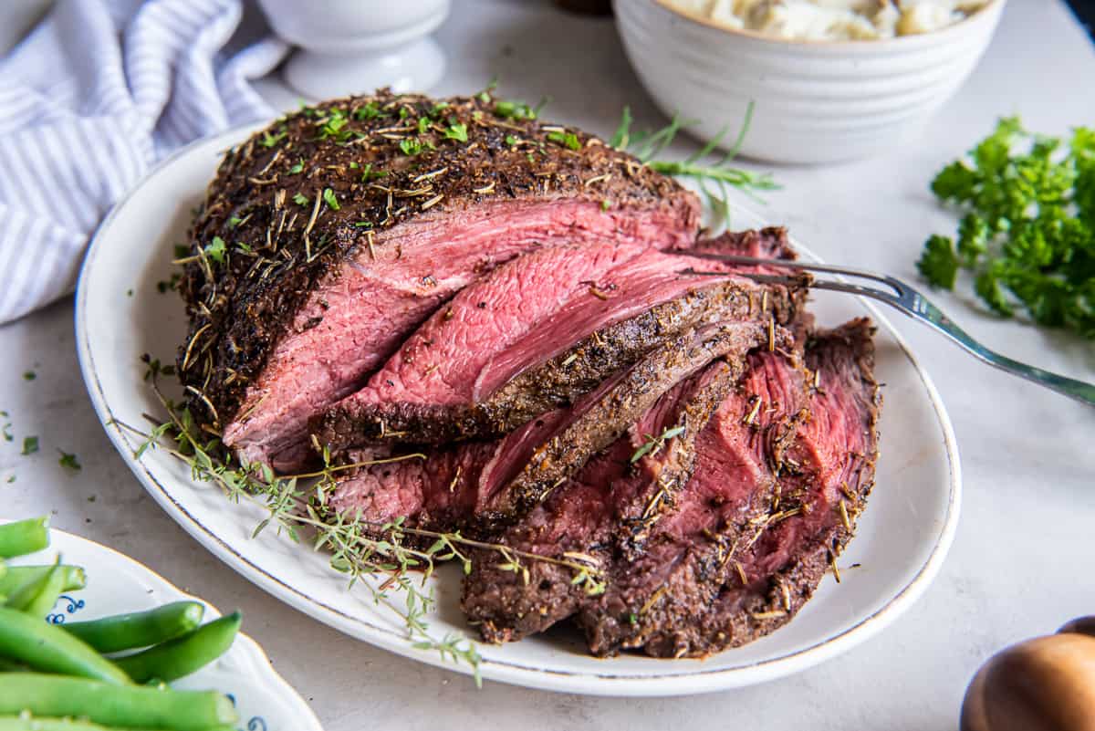 Sliced cross rib roast on a white platter.