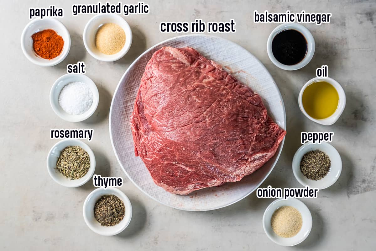 A cross rib roast on a plate surrounded by oil and spices in small bowls with text.