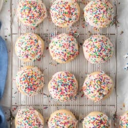 A top down shot of Italian Cookies with icing and rainbow sprinkles on a wire rack.