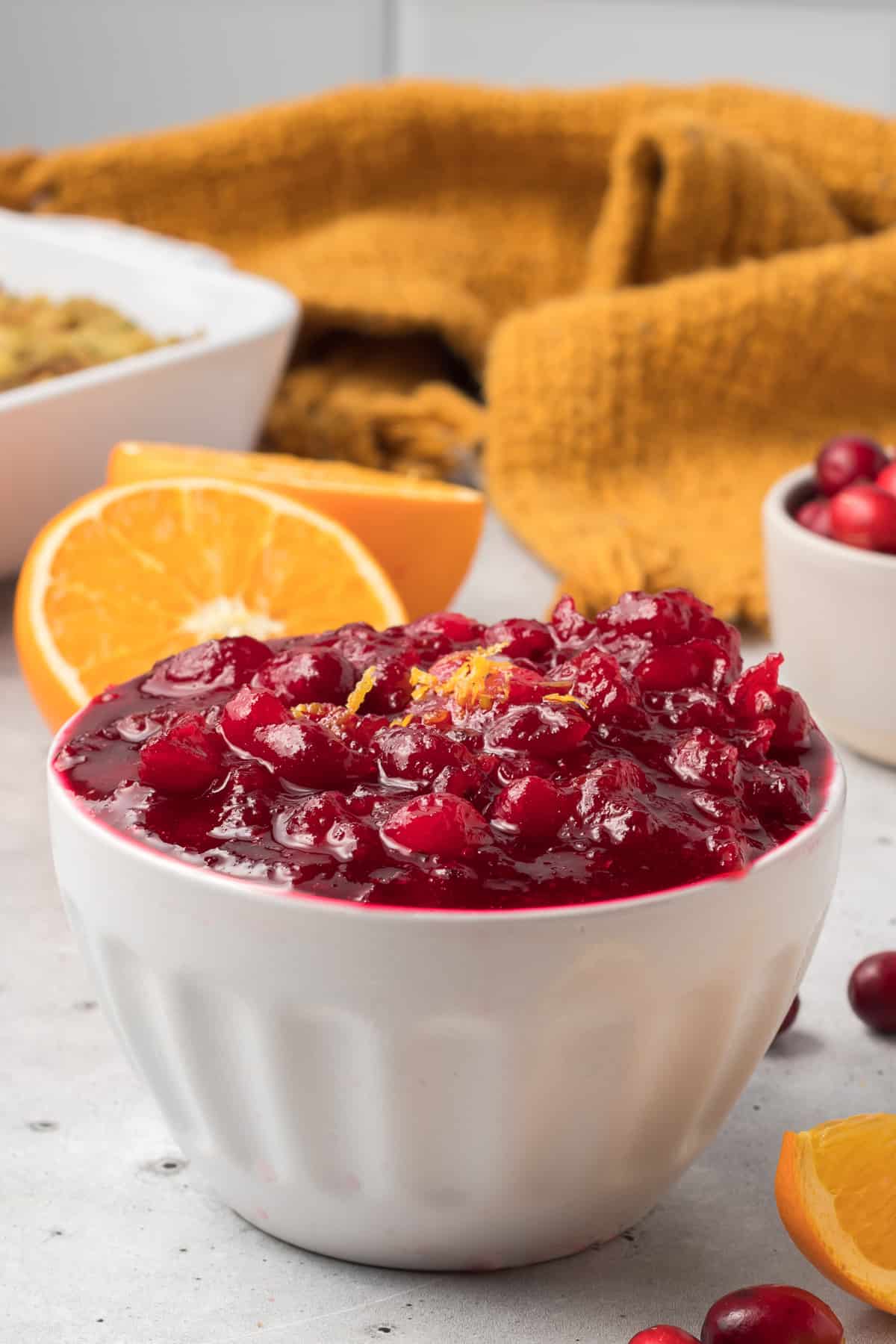 A white bowl filled with cranberry sauce topped with a little orange zest.