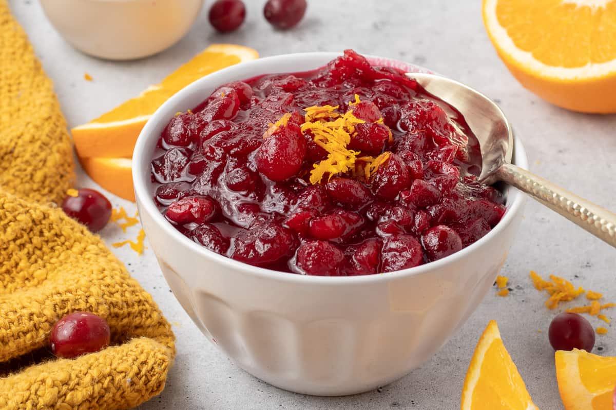 A small mason jar filled with cranberry sauce and topped with orange zest.