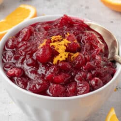 A small mason jar filled with cranberry sauce and topped with orange zest.