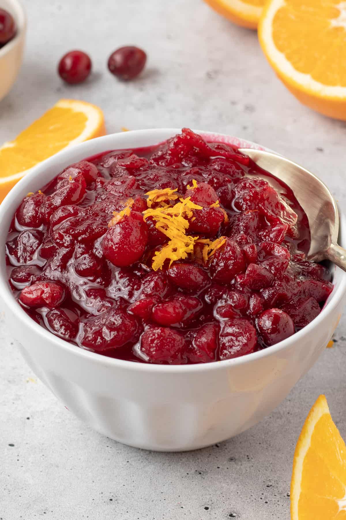 A small mason jar filled with cranberry sauce and topped with orange zest.