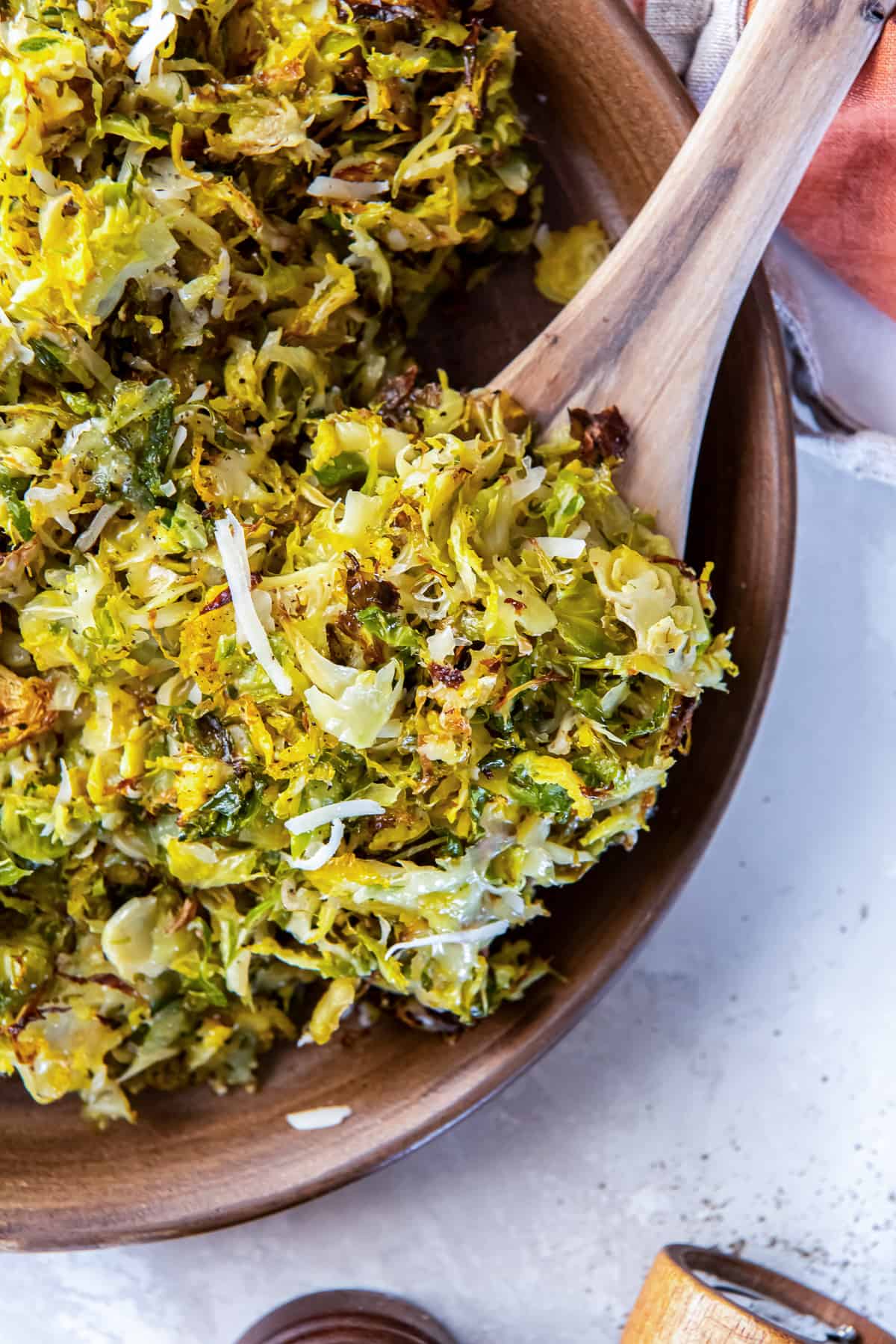 A spoon scooping roasted shredded Brussels sprouts from a bowl.