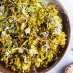 A top down shot of roasted shredded Brussels sprouts with Parmesan in a wooden bowl.