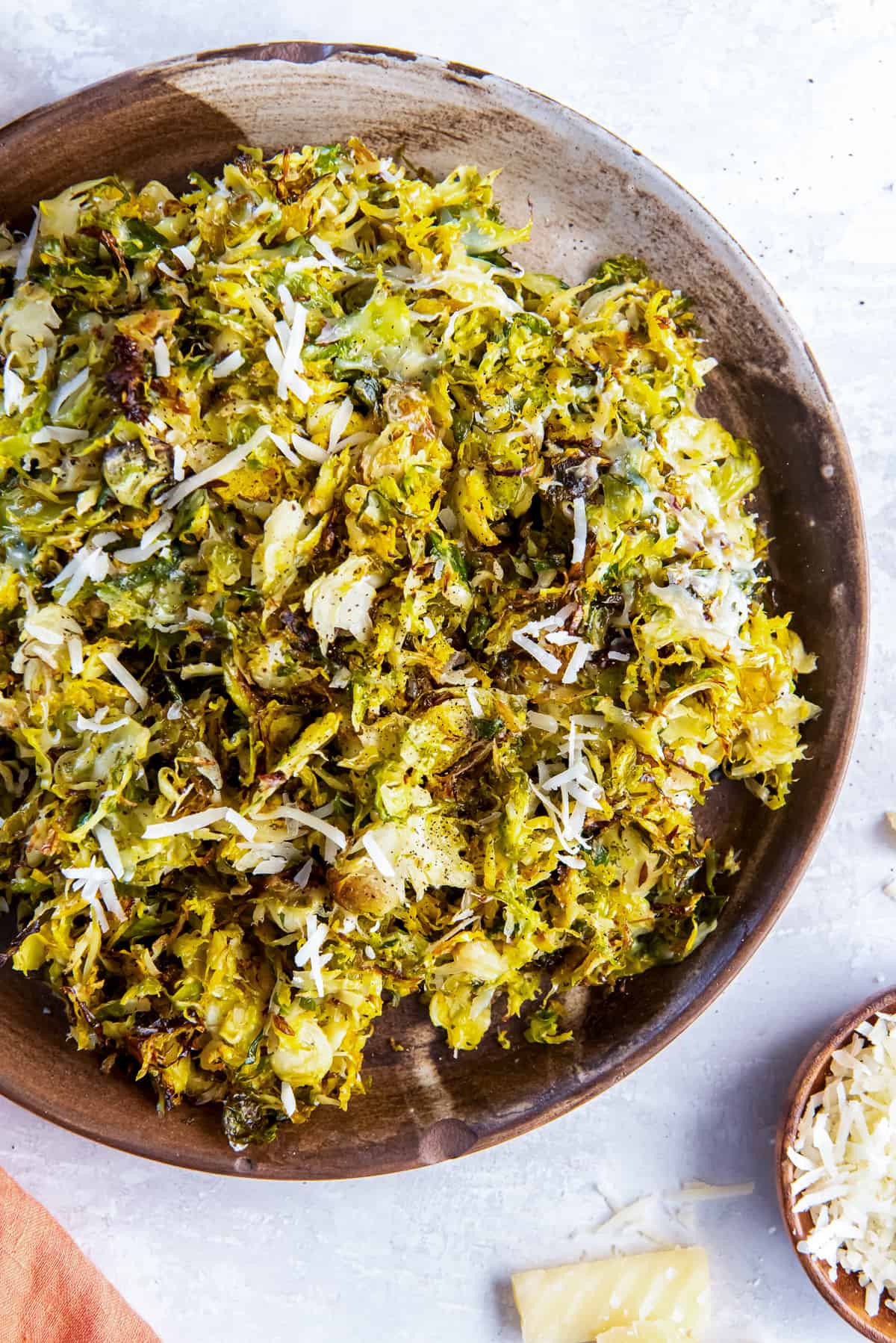 A top down shot of roasted shredded Brussels sprouts with Parmesan in a wooden bowl.