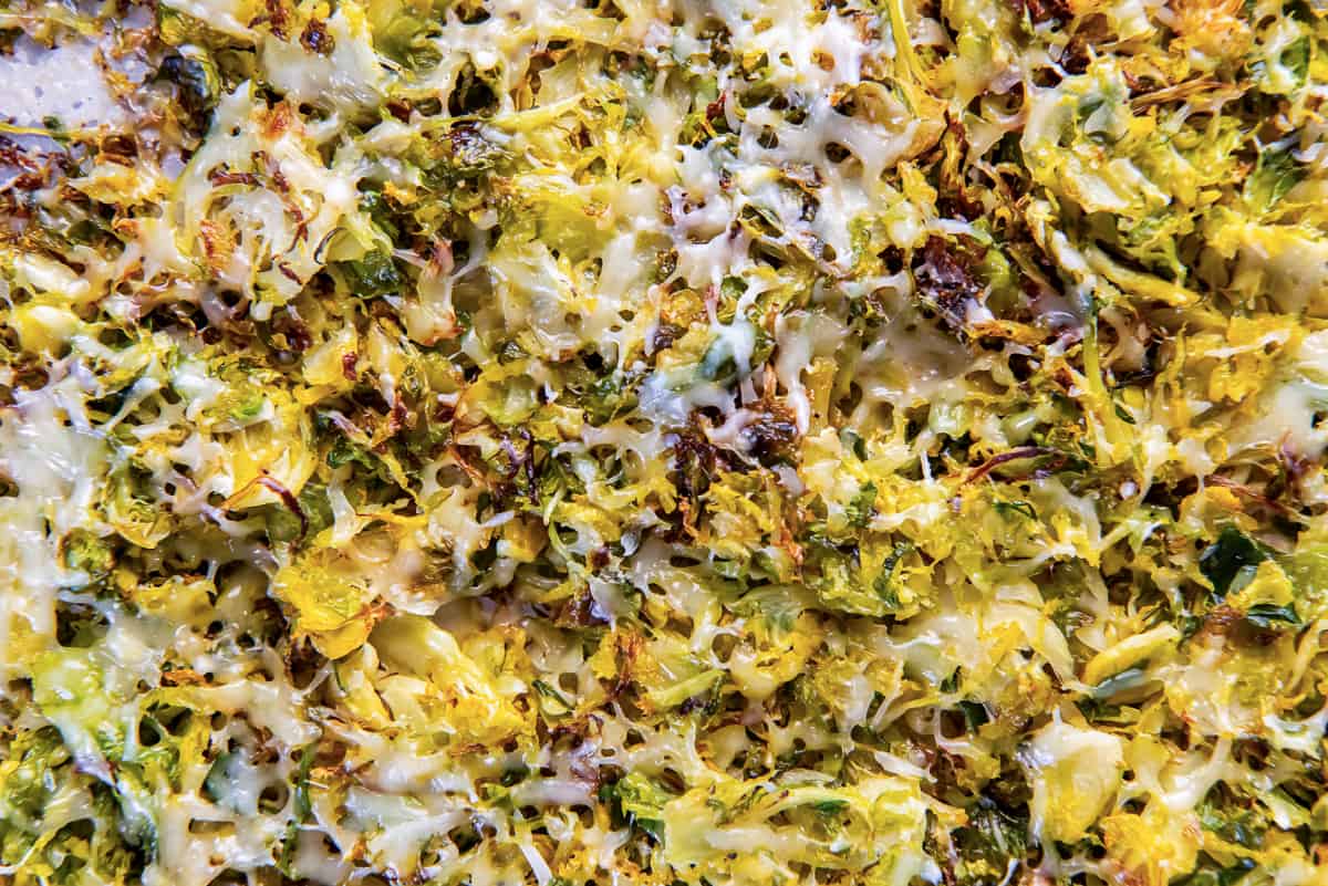 A top down shot of roasted shredded Brussels sprouts with Parmesan cheese on a baking sheet.