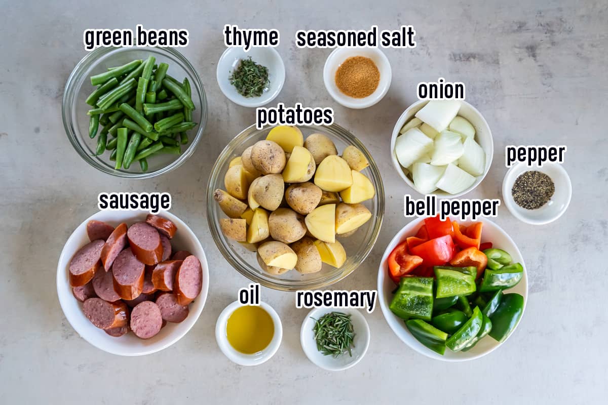Sausage, potatoes, bell peppers and other ingredients in bowls with text.