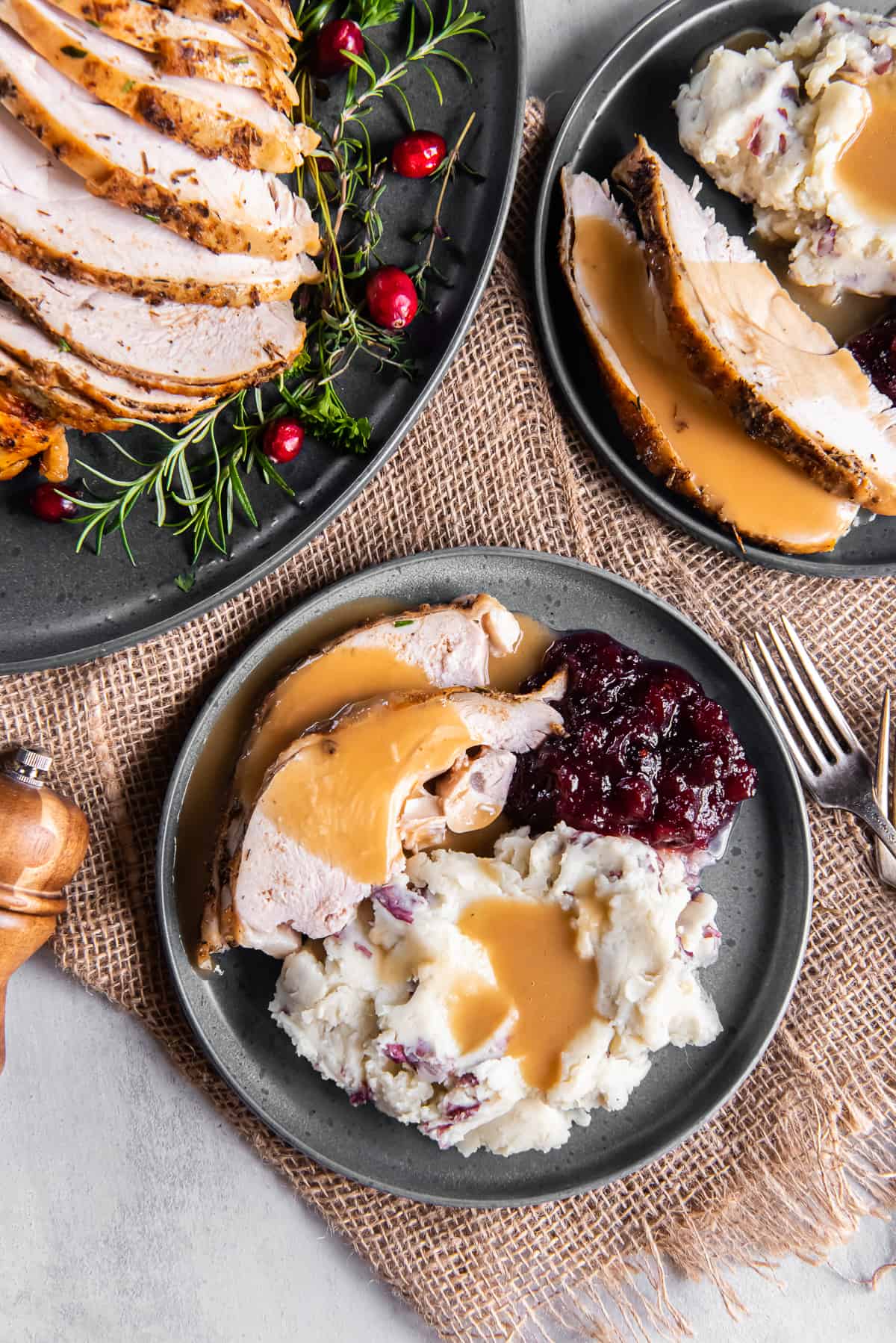 A top down shot of two plates of turkey, mashed potatoes with gravy and cranberry sauce.