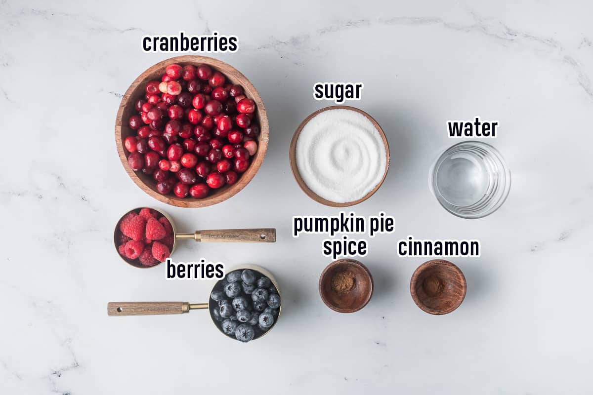 Fresh cranberries, sugar, berries, water, and spices in bowls with text.