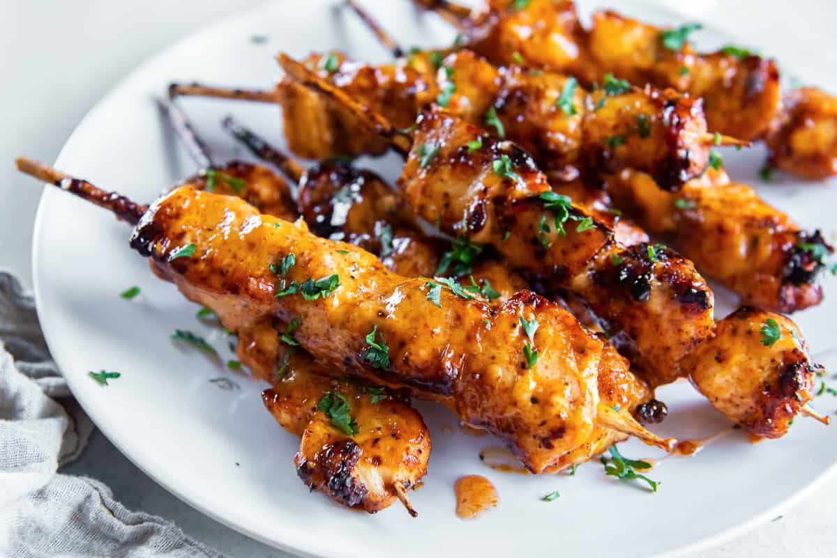 Bang bang chicken skewers on a white plate.