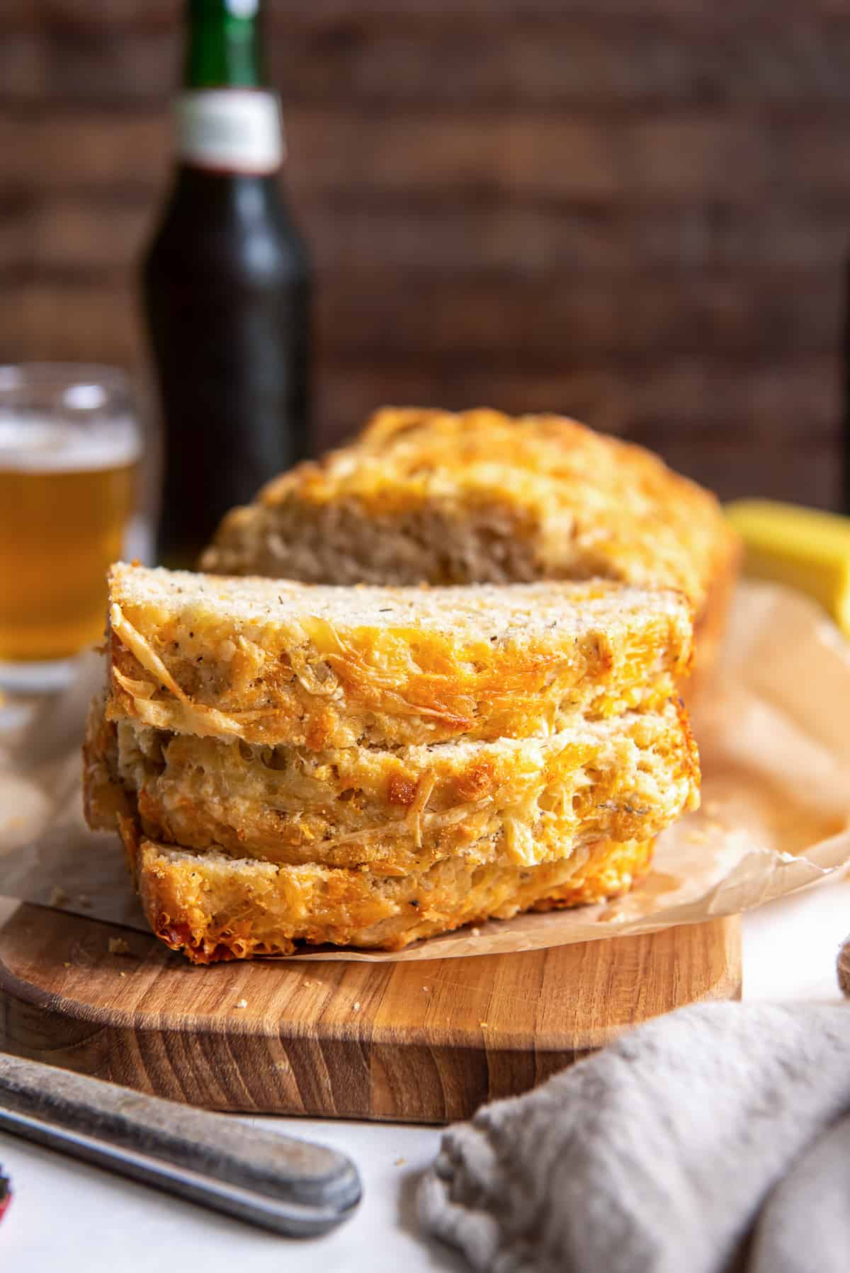 Three slices of cheese beer bread stacked on a cutting board.