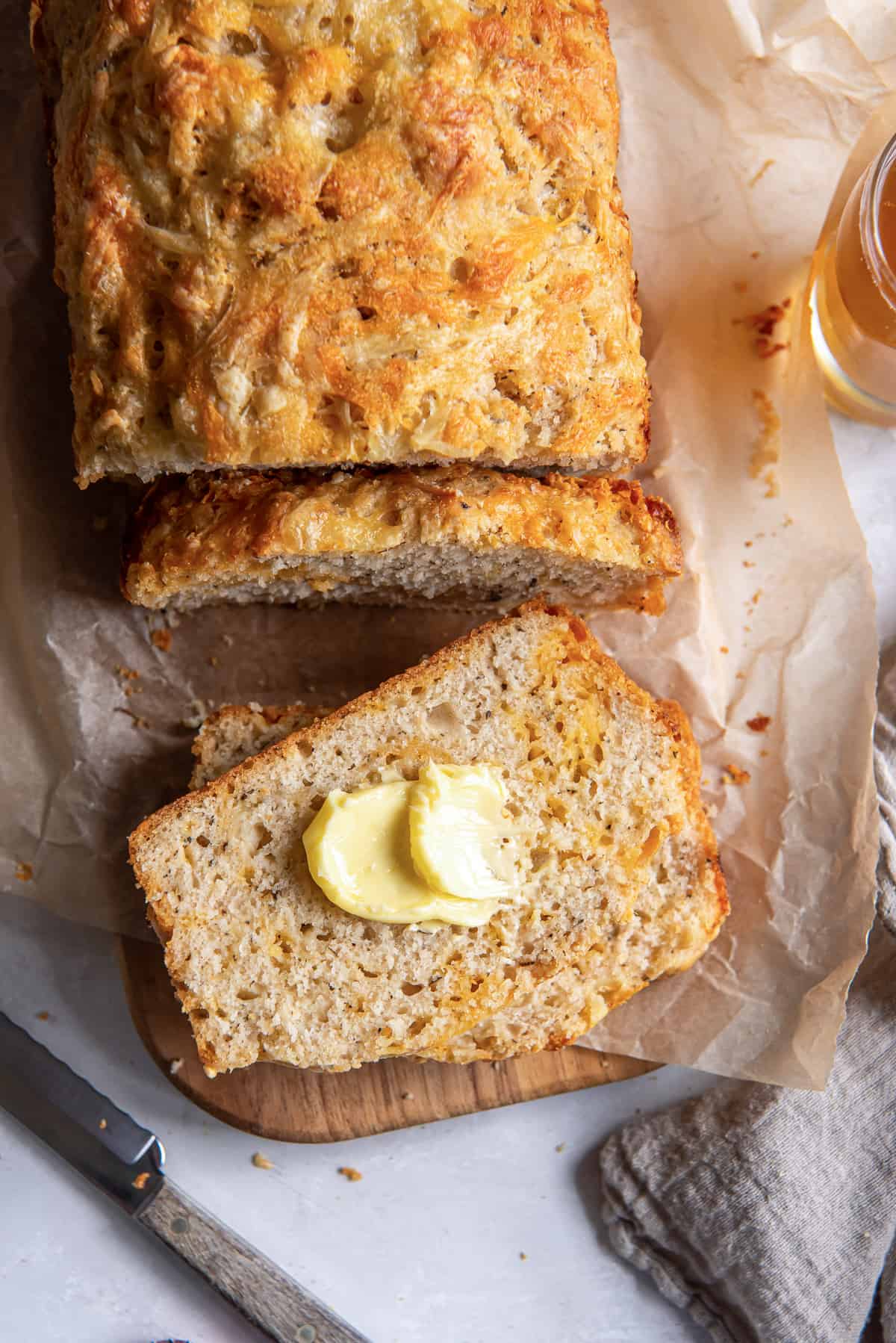 A top down shot of a buttered sliced of cheese beer bread.