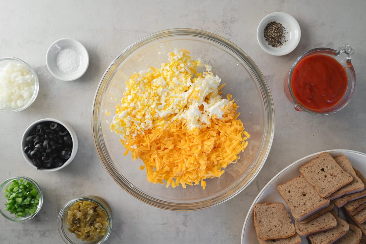 Grated cheese, hard-boiled egg, and butter in a large mixing bowl.