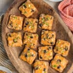 Cheesy cocktail rye appertizers on a wood platter.