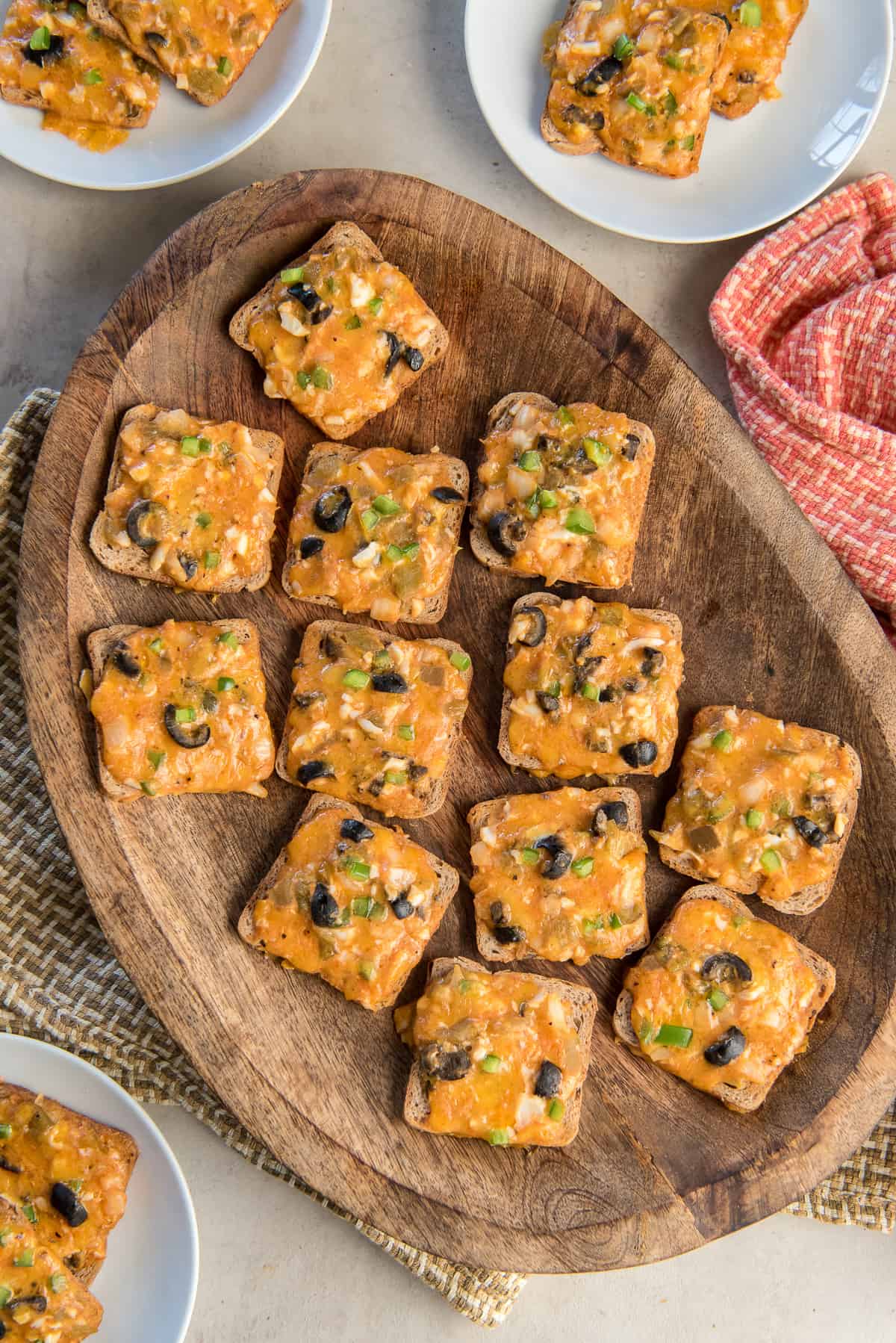 Cheesy cocktail rye appertizers on a wood platter.