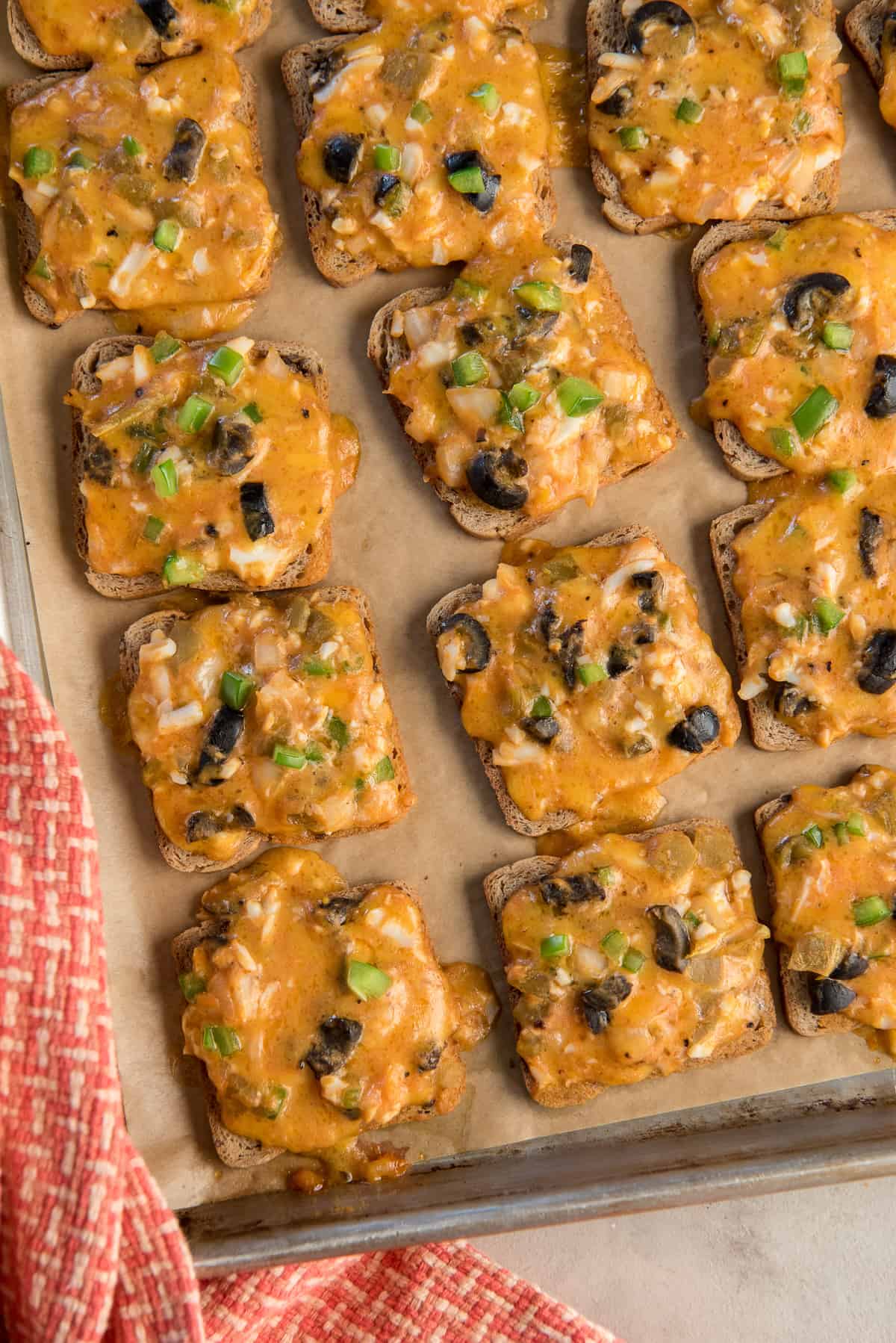 Cheesy cocktail rye appetizers on a baking sheet.