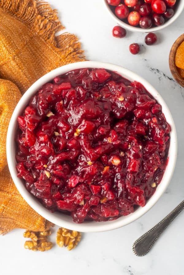 A top down shot of cranberry apricot chutney next to a gold kitchen cloth.