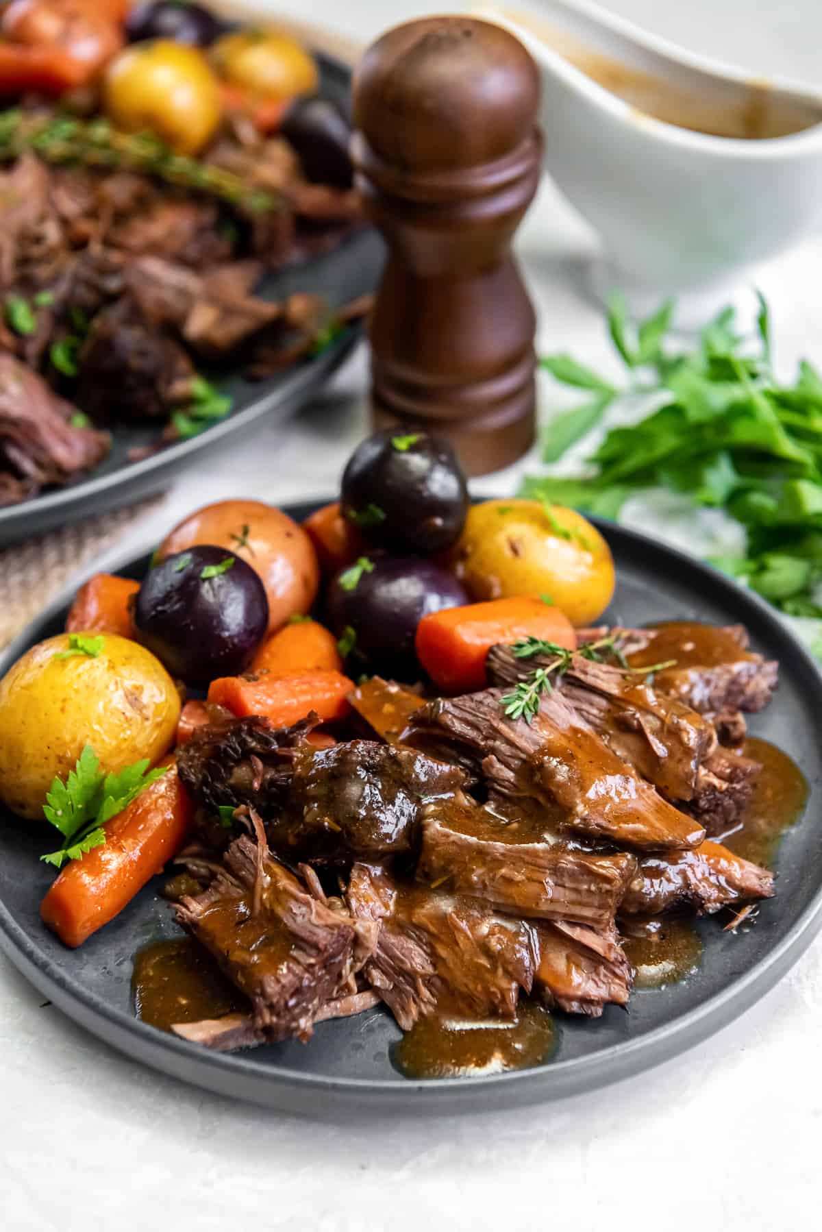 A dinner plate filled with pot roast with gravy, carrots and potatoes.