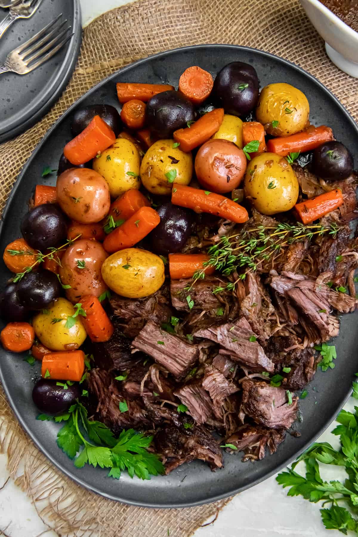 A top down shot of chunks of pot roast on a platter with colorful potatoes and carrots.