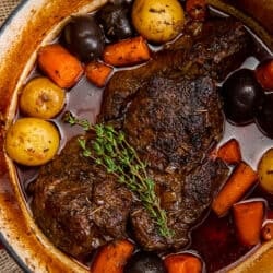 A top down shot of a pot roast with vegetables in a Dutch oven.