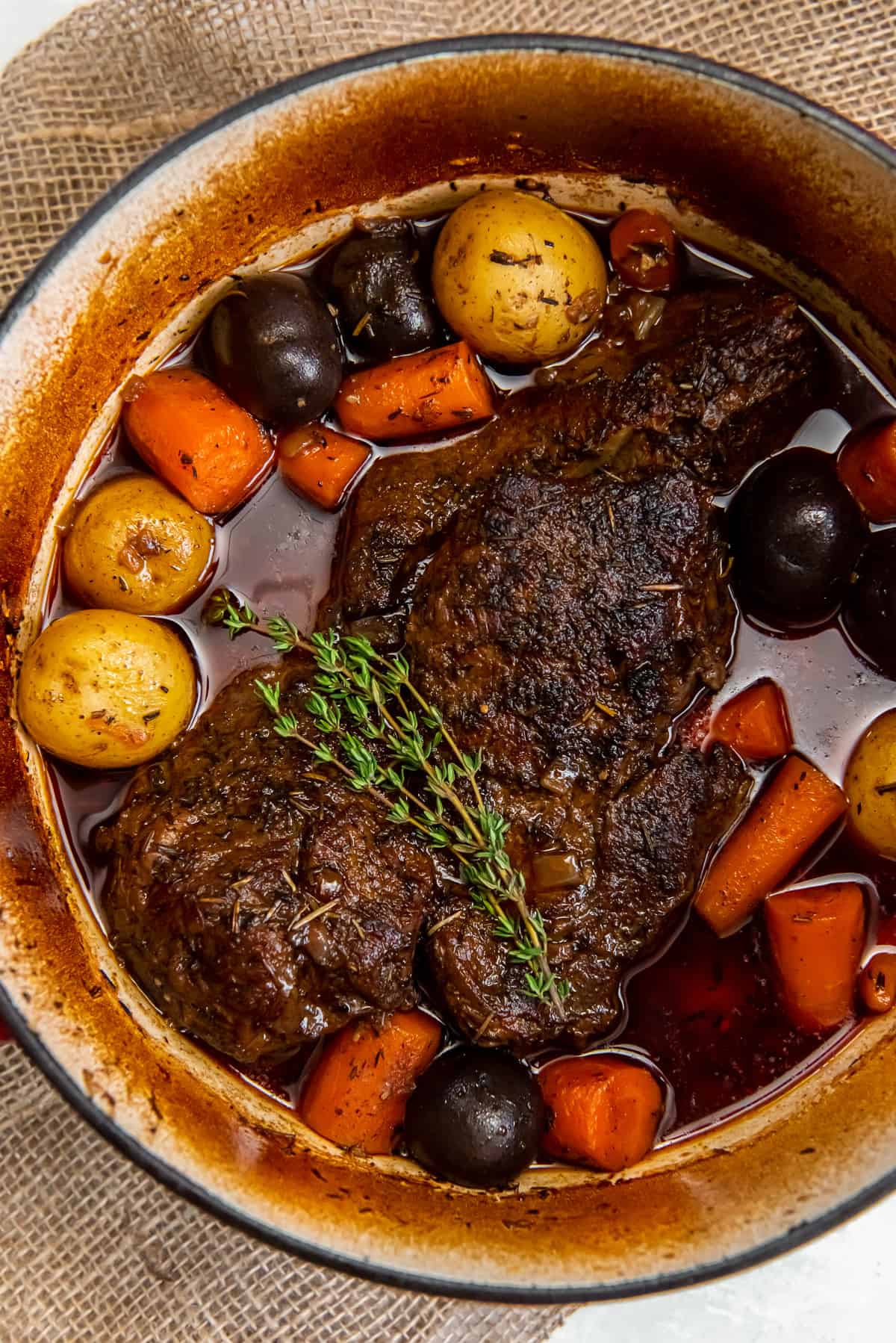 A top down shot of a pot roast with vegetables in a Dutch oven.