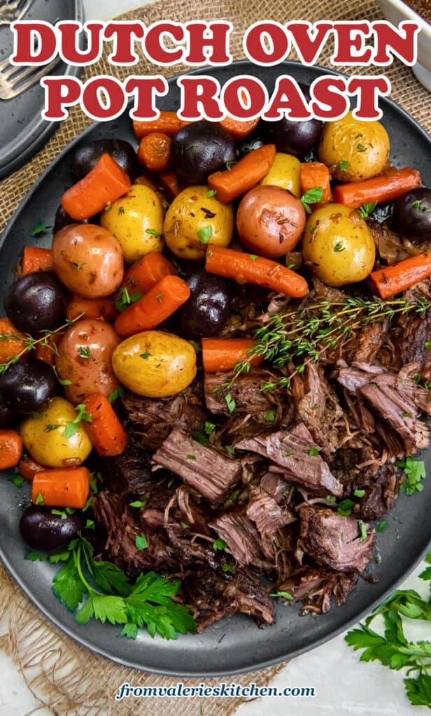 A top down shot of chunks of pot roast on a platter with colorful potatoes and carrots with text.