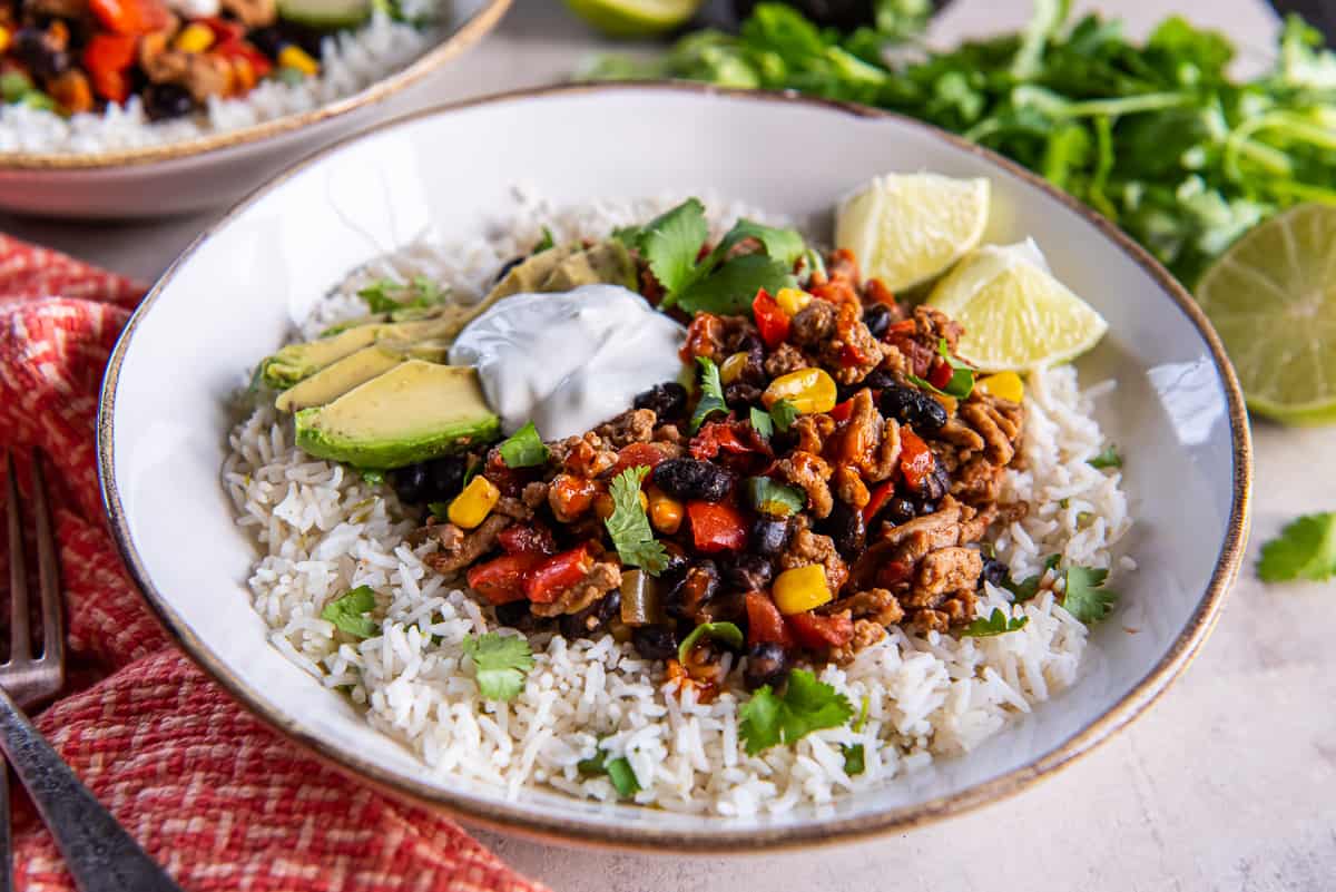 A Southwest ground turkey mixture on cilantro lime rice in a white bowl.