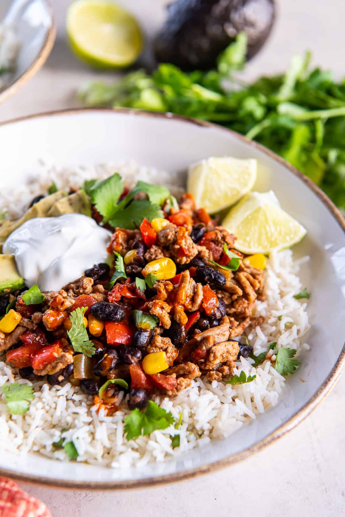 A close up shot of a ground turkey taco bowl topped with avocado and sour cream.