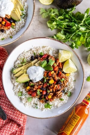 A top down shot of a ground turkey taco bowl topped with avocado and sour cream.