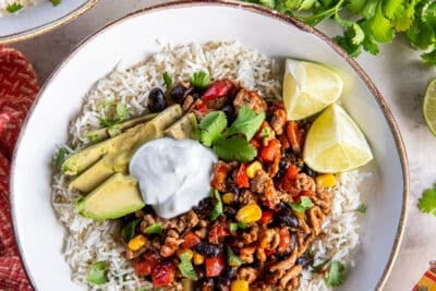 A top down shot of a ground turkey taco bowl topped with avocado and sour cream.