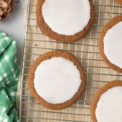 A close up top down shot of iced molasses cookies on a wire rack.