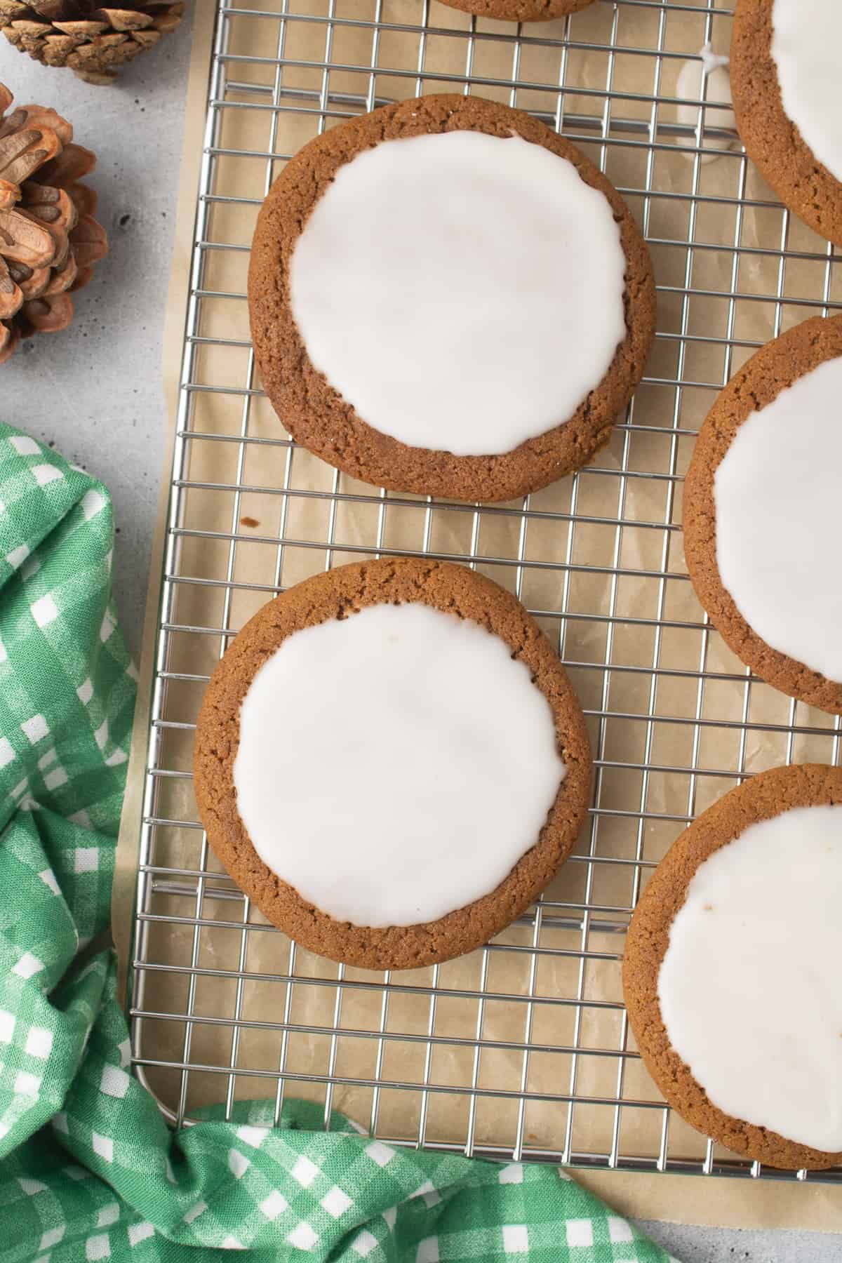 A close up top down shot of iced molasses cookies on a wire rack.