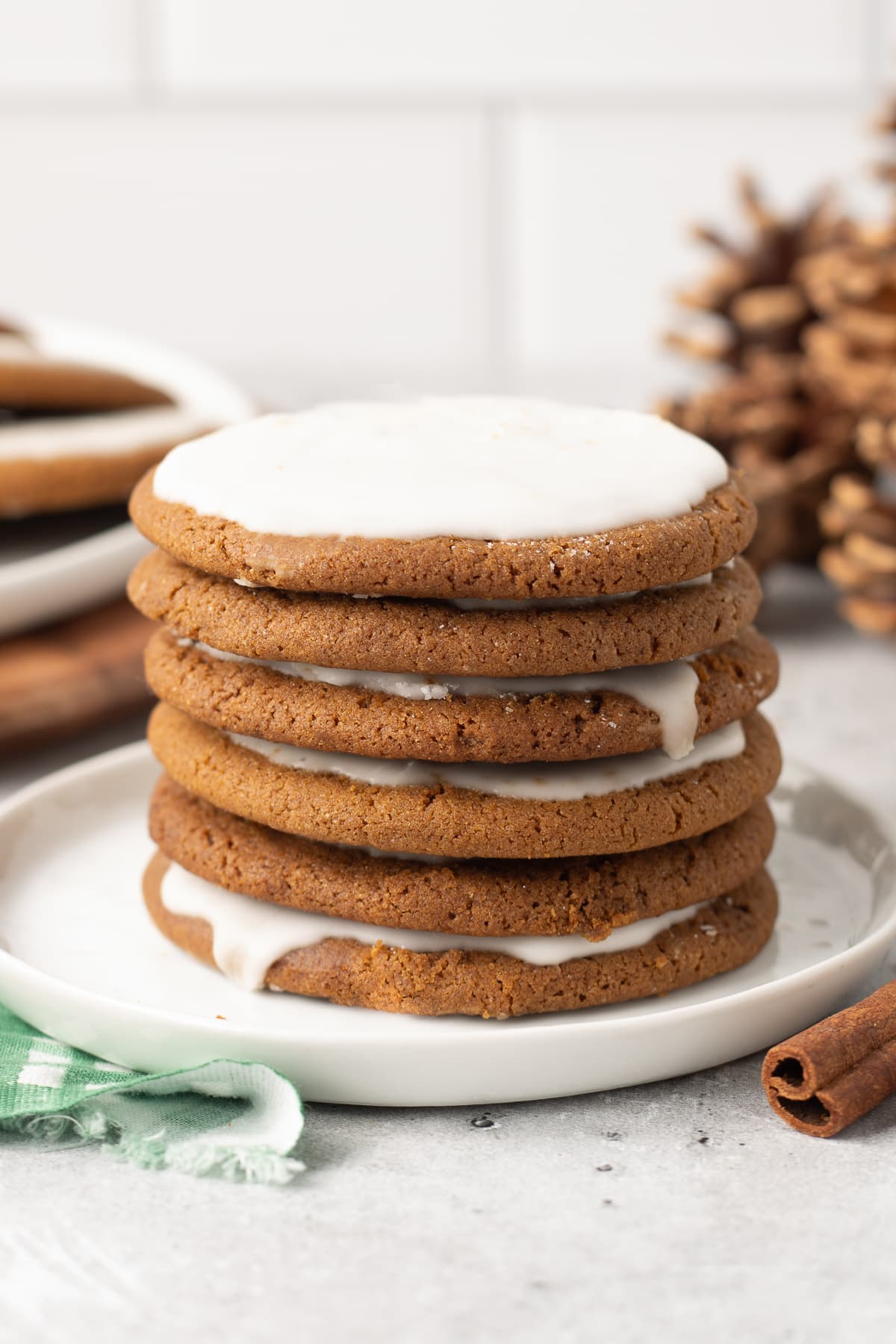 A stack of iced molasses cookies on a white plate.
